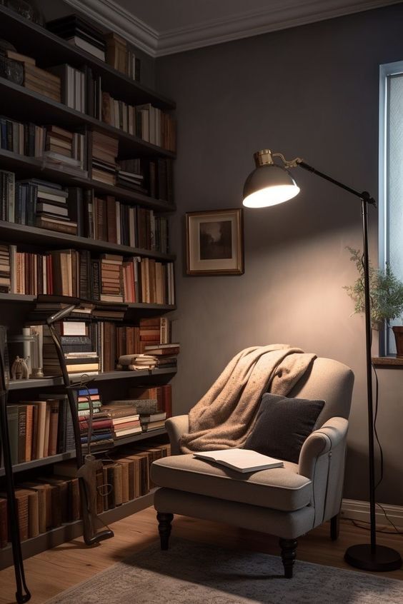 Bibliothèque avec lampe sur pied et fauteuil recouvert d'un plaid